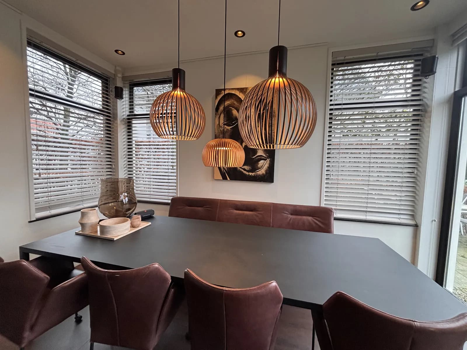 Houten jaloezieën in een eetkamer met hanglampen