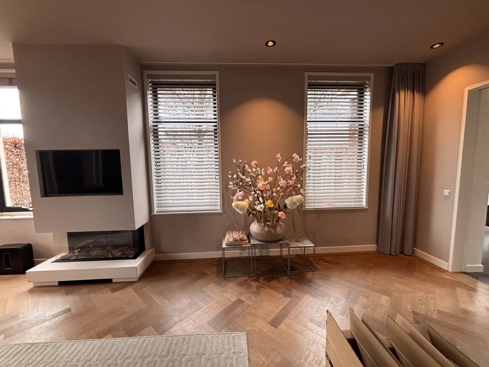 Woonkamer met houten jaloezieën en visgraatvloer